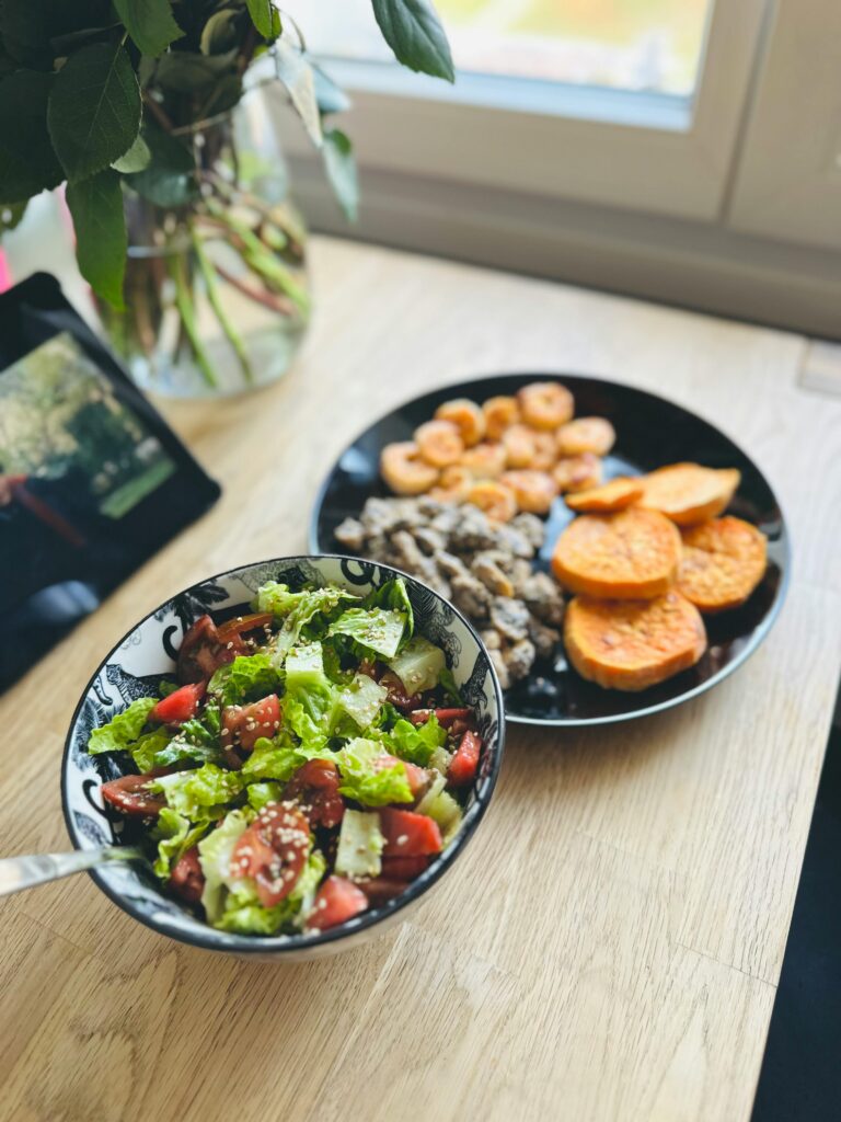 Fresh salad with tomatoes and lettuce, served with sweet potatoes and mushrooms in a home setting.